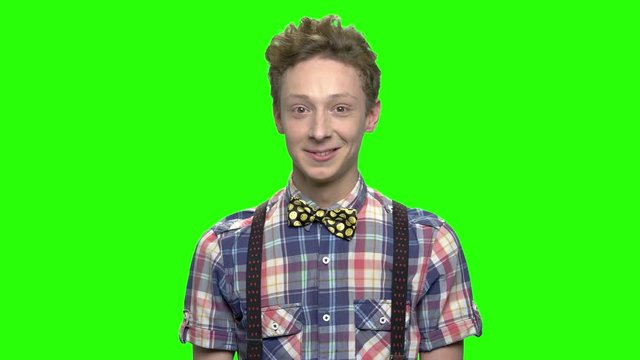 Positive smiling teenage boy in fashionable clothes. Checkered shirt, suspenders and bow. Green screen hromakey background for keying.