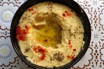 Hummus, chickpea dip, with spices in a black plate on the table. Top view.  Traditional classic hummus. Vegetarian dish