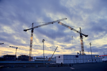Construction cranes against the dark sky background