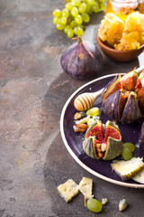 Gourmet appetizer of baked figs with goat cheese,walnuts and honey on ceramic plate and brown concrete background, top view with copy space