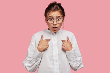 Photo of indignant beautiful Caucasian woman points at herself with discontent expression, being...