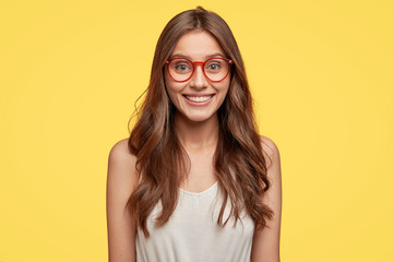 Indoor shot of good looking young Caucasian woman has broad smile, being in good mood after date...