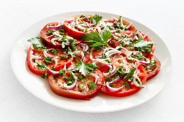 round slices of tomatoes freshly marinated in white vine vinegar, oilve oil, red onion, chopped parsley, and garlic 