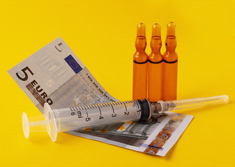 photo on a yellow background of money to buy medicine and a syringe for health