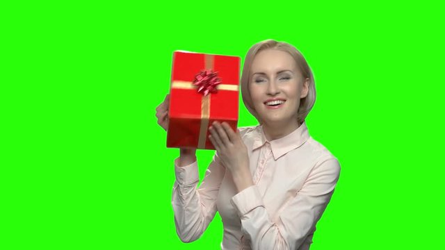 Woman shaking gift box with excitement. Mature business woman recieved desirable gift in red box. Green hromakey background for keying.