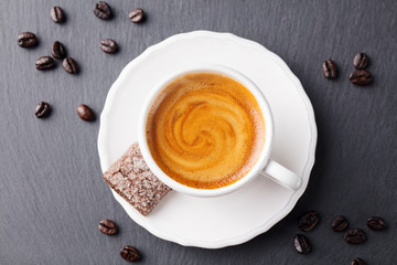 Coffee espresso in white cup on black slate background. Top view.