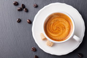 Coffee espresso in white cup on black slate background. Top view. Copy space.