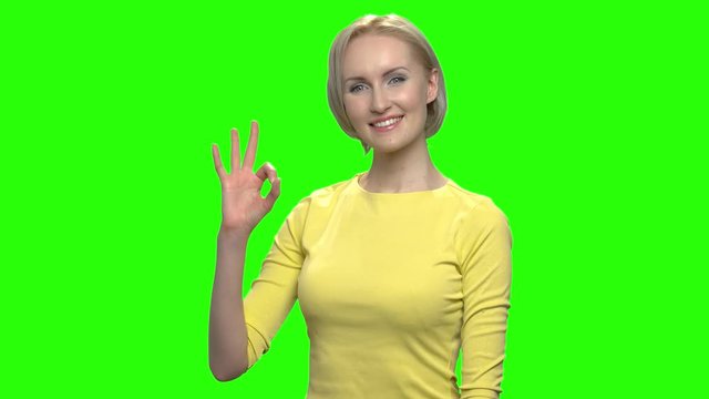 Happy mature woman giving ok gesture. Green hromakey background for keying.