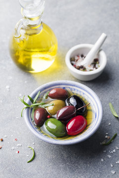 Olives assortment in bowl with oil. Stone background.
