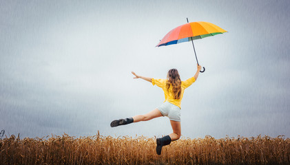 Frau freut sich über den Regen und springt mit dem Regenschirm in die Luft