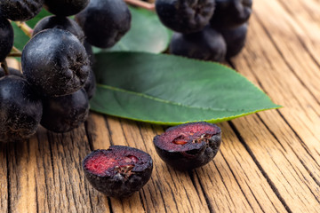 Berries of black mountain ash on a wooden background. Aronia melanocarpa. Therapeutic properties of black mountain ash. Super antioxidant.