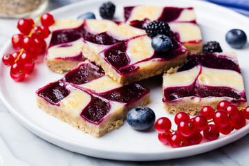 Oatmeal, oat bars with fresh berries on a white plate. Marble background. Healthy breakfast.
