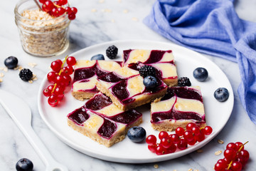 Oatmeal, oat bars with fresh berries on a white plate. Marble background. Healthy breakfast.