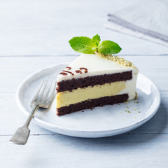 White chocolate cake with fresh mint leaf on a plate. Wooden background.