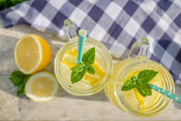 Lemonade in jars of hipster for jam on a background of green grass. Concept: picnic with refreshing drinks