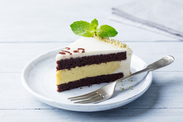 Chocolate, pistachio cake with fresh mint leaf on a plate. Wooden background.