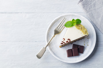 White chocolate cake with fresh mint leaf on a plate. Wooden background. Copy space. Top vew.