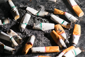 Close-up Cigarettes butts wastes dumped and scattered all over the floor. Smoking is bad for your health.