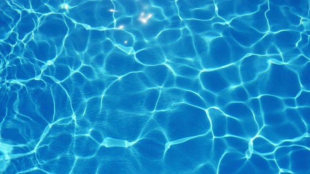 A marvelous view of sky blue waters in a swimming pool with shining web altering its shape beautifully in summer in slow motion
