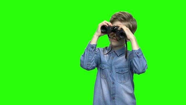 Child boy tourist looking through binoculars. Green hromakey background for keying.
