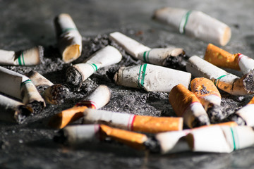 Close-up Cigarettes butts wastes dumped and scattered all over the floor. Smoking is bad for your health.