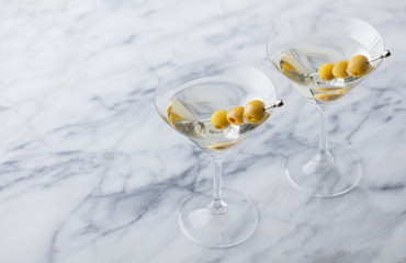 Martini cocktail with green olives on marble table background. Copy space.