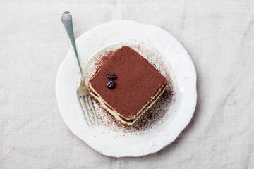 Tiramisu, traditional Italian dessert on a white plate. Copy space. Top view.