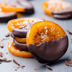 Candied orange slices in chocolate. Slate background. Close up.