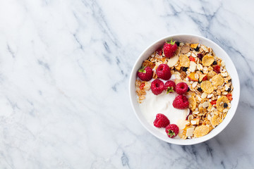Healthy breakfast. Fresh granola, muesli with yogurt and berries on marble background. Top view. Copy space.