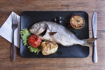 Dorado fish on a black plate