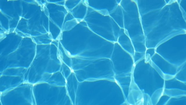 An enigmatic view of swinging  light bue waters in a pool with shimmering lines shaping a cheery background in slow motion