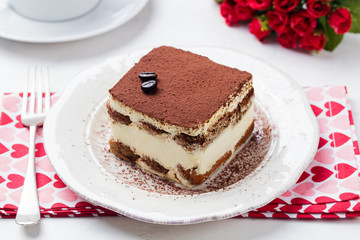 Tiramisu, traditional Italian dessert on a white plate.