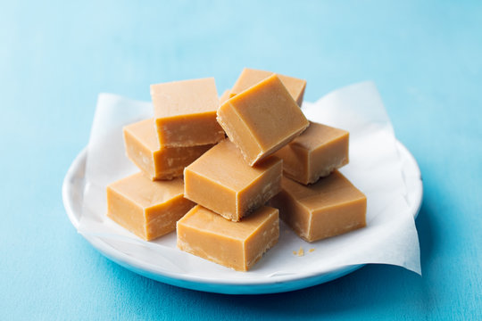 Fresh caramel fudge candies on a plate. Blue background. Close up.