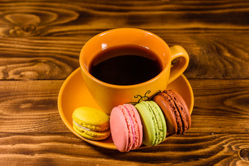 Cup of coffee and french macaroons on wooden table