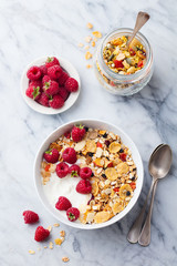 Healthy breakfast. Fresh granola, muesli with yogurt and berries on marble background. Top view.