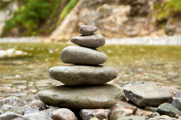 A close-up view of stones folded into a pyramid or pile, with a mountain river