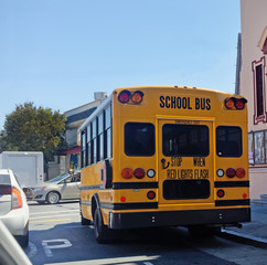 Naklejka na ściany i meble Rear view of school bus in city traffic.