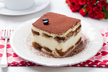Tiramisu, traditional Italian dessert on a white plate. Close up.