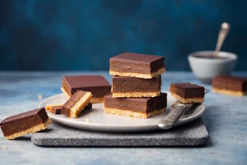 Gordijnen Chocolate caramel slices, bars, millionaires shortbread on a grey plate. Blue background. © annapustynnikova