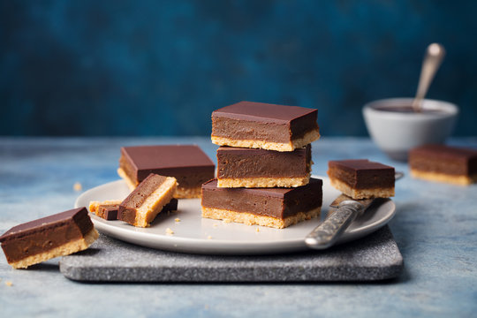 Chocolate caramel slices, bars, millionaires shortbread on a grey plate. Blue background.