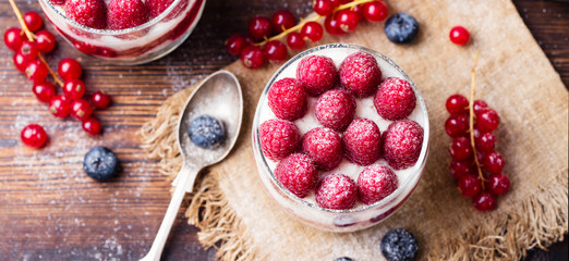 Raspberry dessert, cheesecake, trifle, mouse in a glass on a wooden background. Top view.