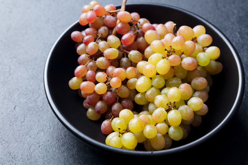 Fresh grape in bowl on a black stone background. Close up.