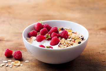 Healthy breakfast. Fresh granola, muesli with yogurt and berries on wooden background. Close up.