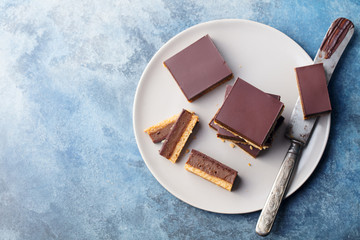 Chocolate caramel slices, bars, millionaires shortbread on a grey plate. Blue background. Top view.
