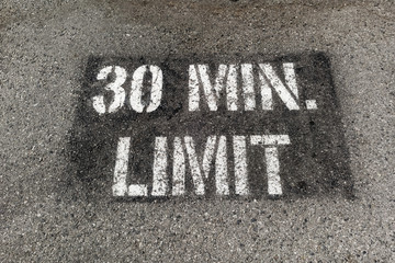 30 MIN. LIMIT parking sign painted on parking lot asphalt.