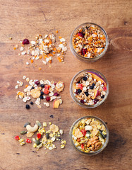 Assortment of granola, muesli in glass jars. Organic oats with apples, berries and nuts. Top view.
