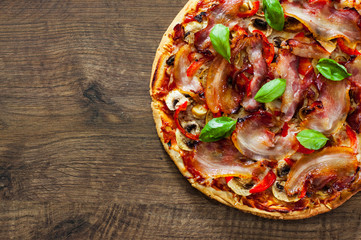 Pizza with Mozzarella cheese, mushrooms, bacon, Tomatoes, pepper, Spices and Fresh Basil. Italian pizza on wooden background.