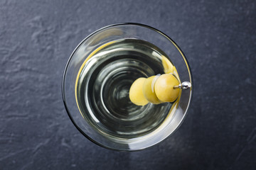 Martini cocktail with green olives. Slate background. Top view. Close up.