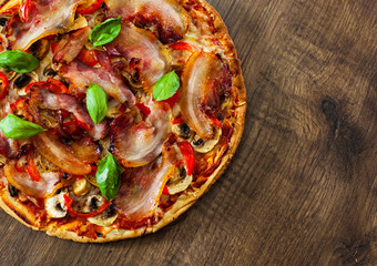 Pizza with Mozzarella cheese, mushrooms, bacon, Tomatoes, pepper, Spices and Fresh Basil. Italian pizza on wooden background.