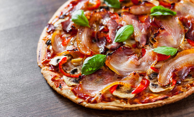 Pizza with Mozzarella cheese, mushrooms, bacon, Tomatoes, pepper, Spices and Fresh Basil. Italian pizza on wooden background.